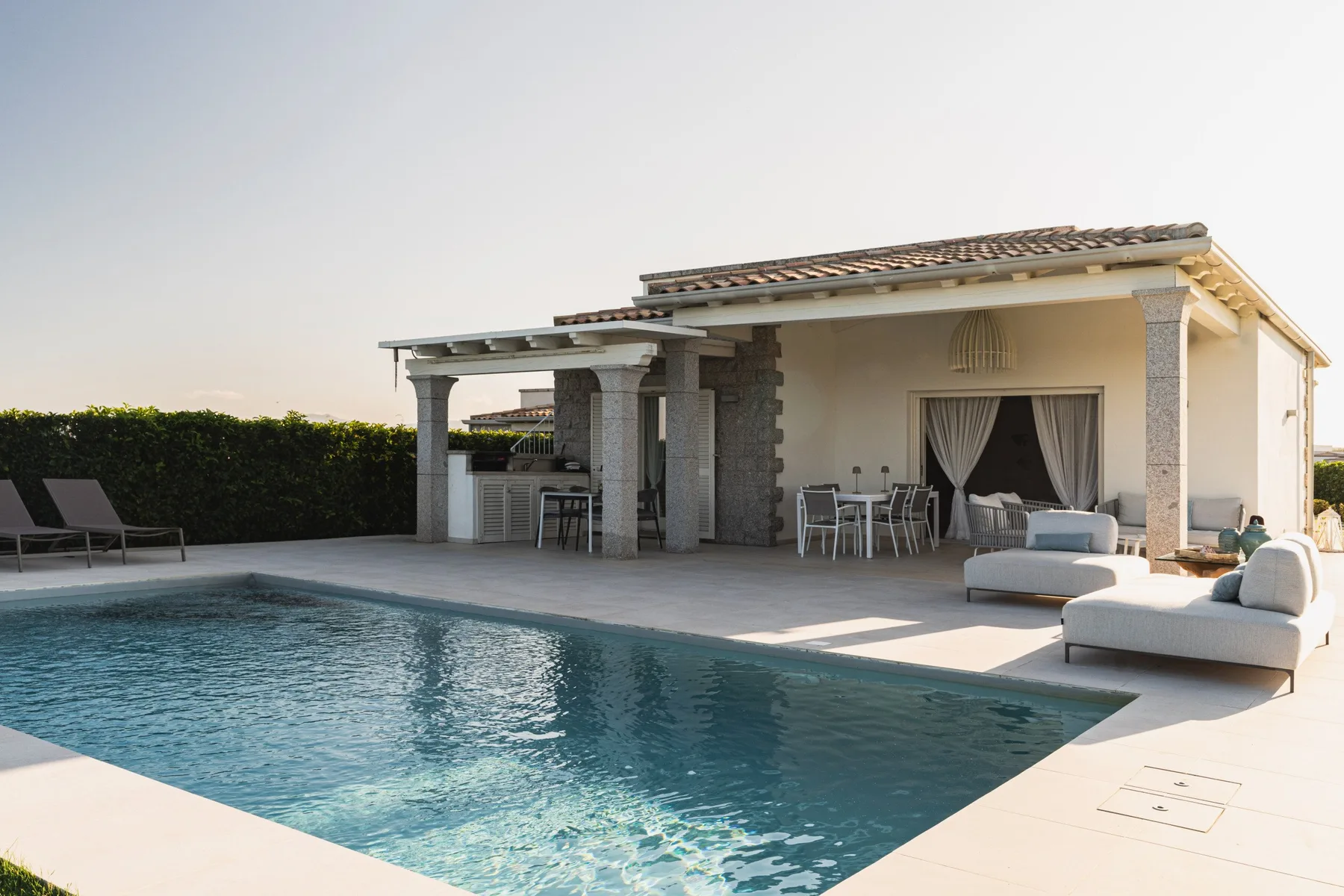 A swimming pool beside a covered patio with outdoor seating.