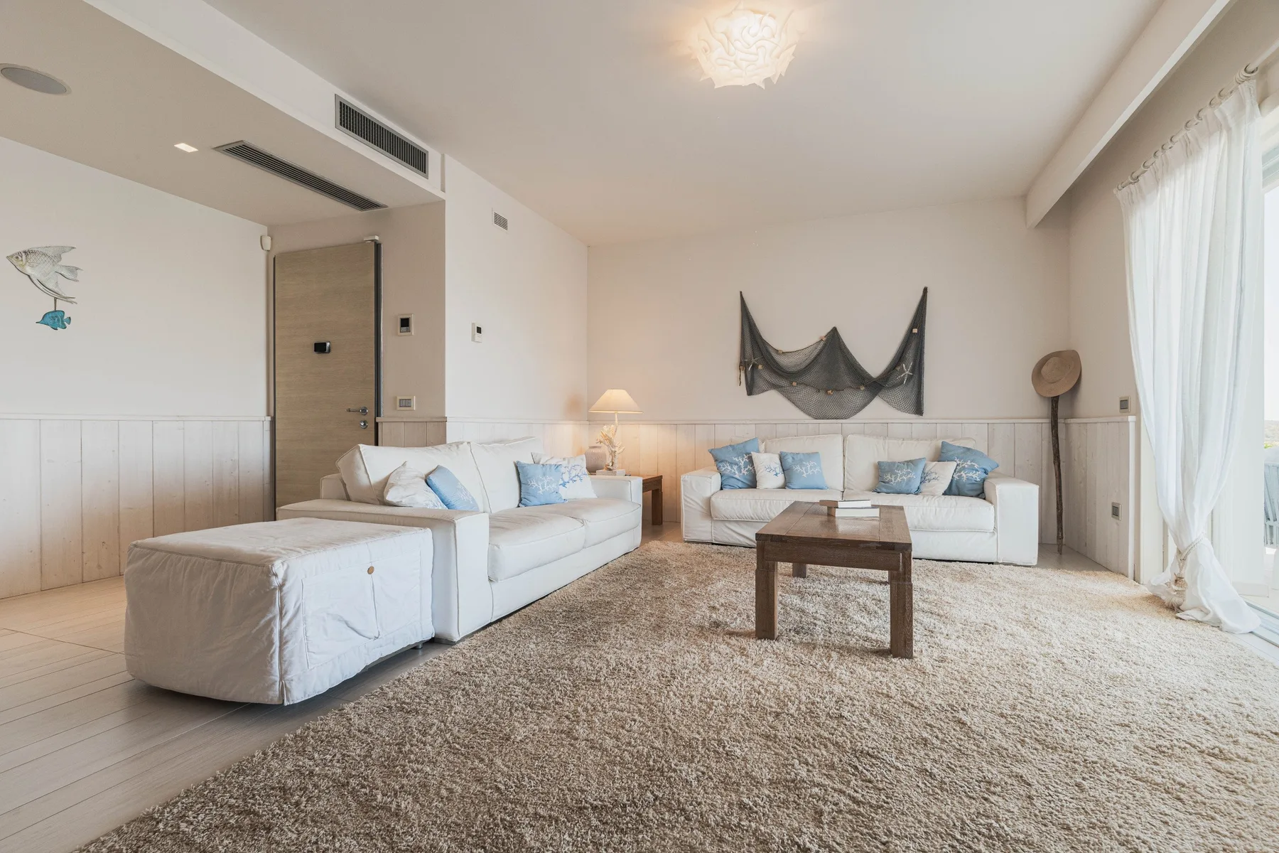 A bright living room with white seating around a wooden coffee table.