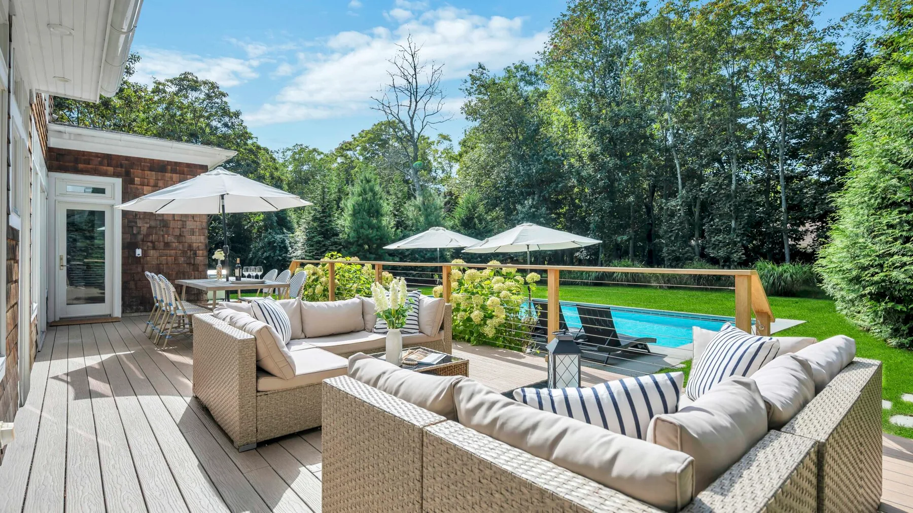 Una terraza amueblada da a una piscina y a los árboles que la rodean.