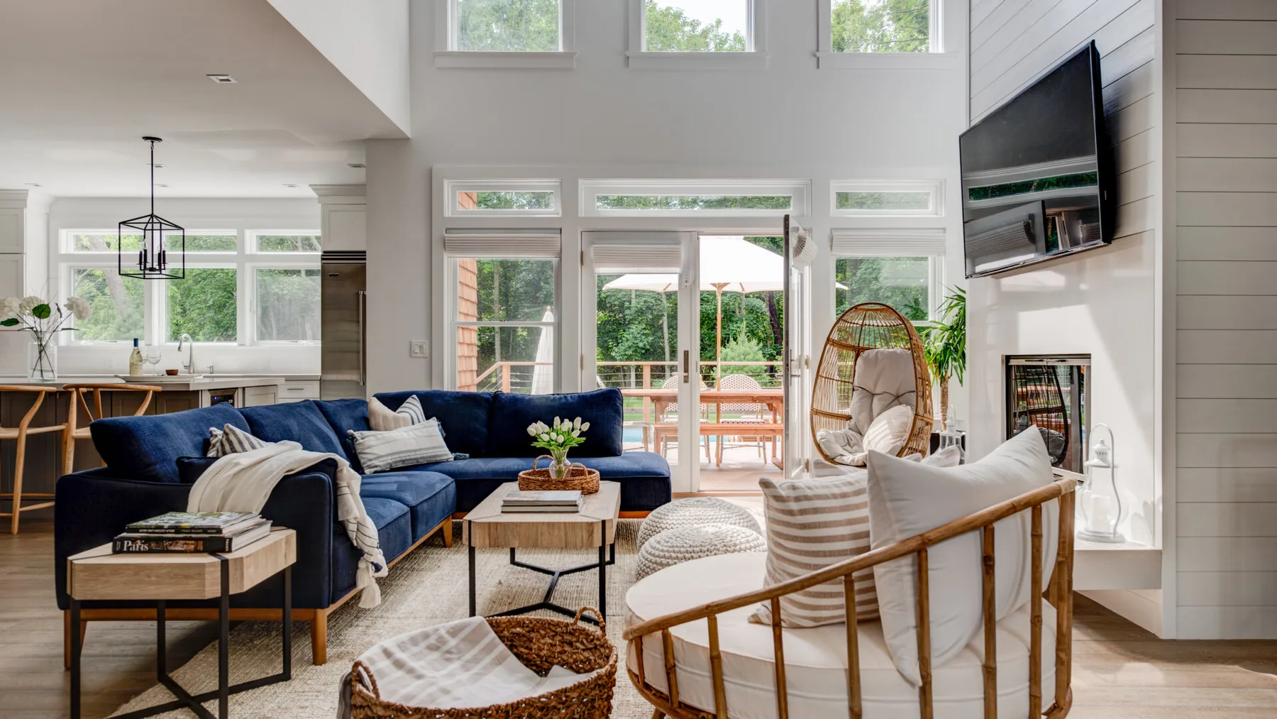 A bright living room with blue seating, large windows, and a hanging chair.