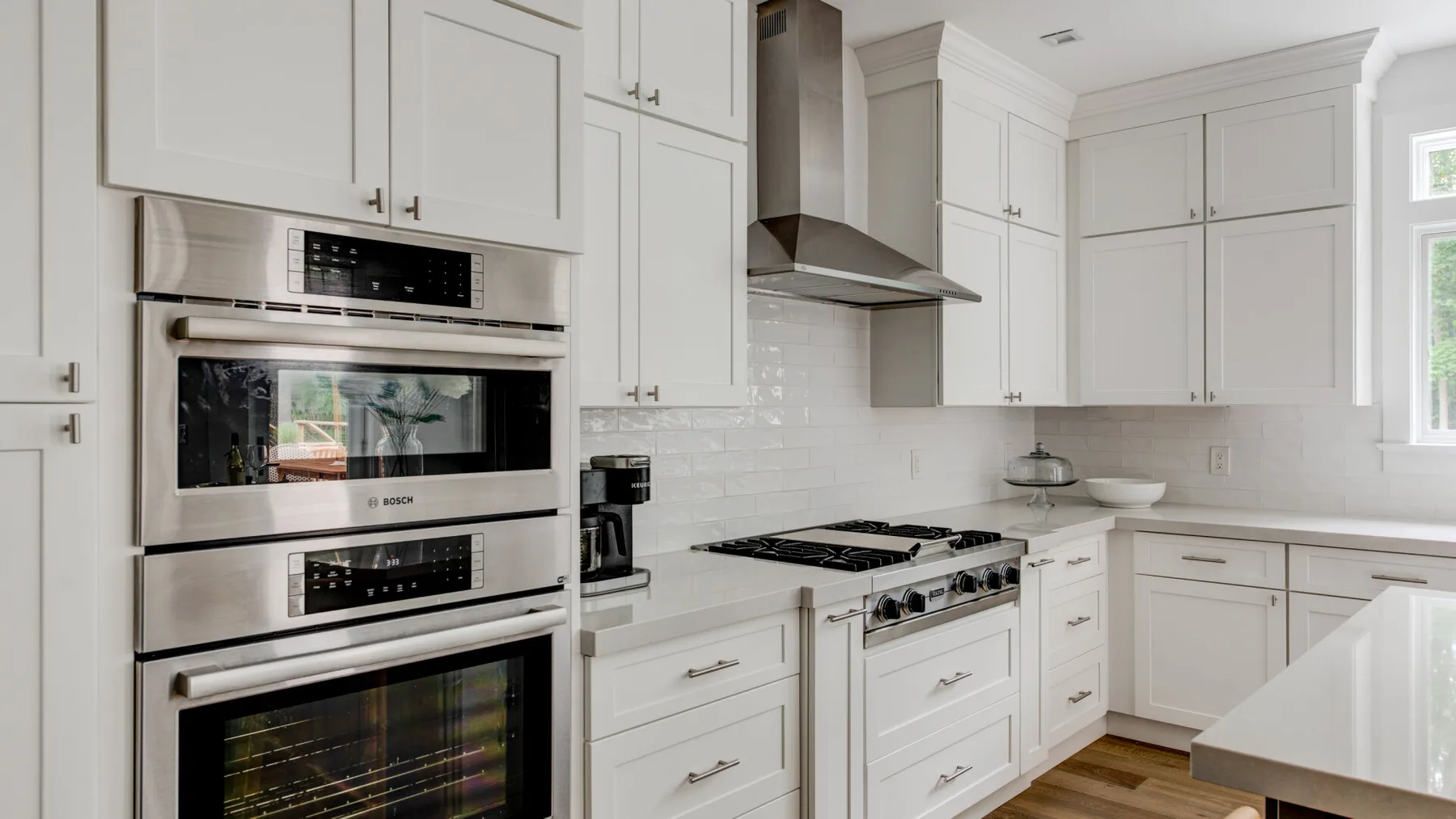Una cocina luminosa con armarios blancos, electrodomésticos de acero inoxidable y una placa de cocción.