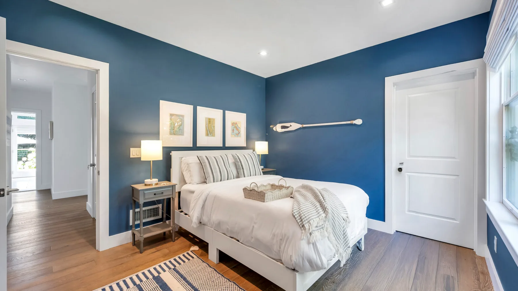 Un dormitorio con una cama, paredes azules y una puerta abierta a un pasillo.