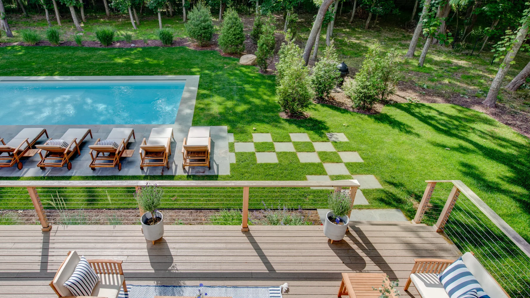 Una terraza con asientos al aire libre da a una piscina y un césped ajardinado.