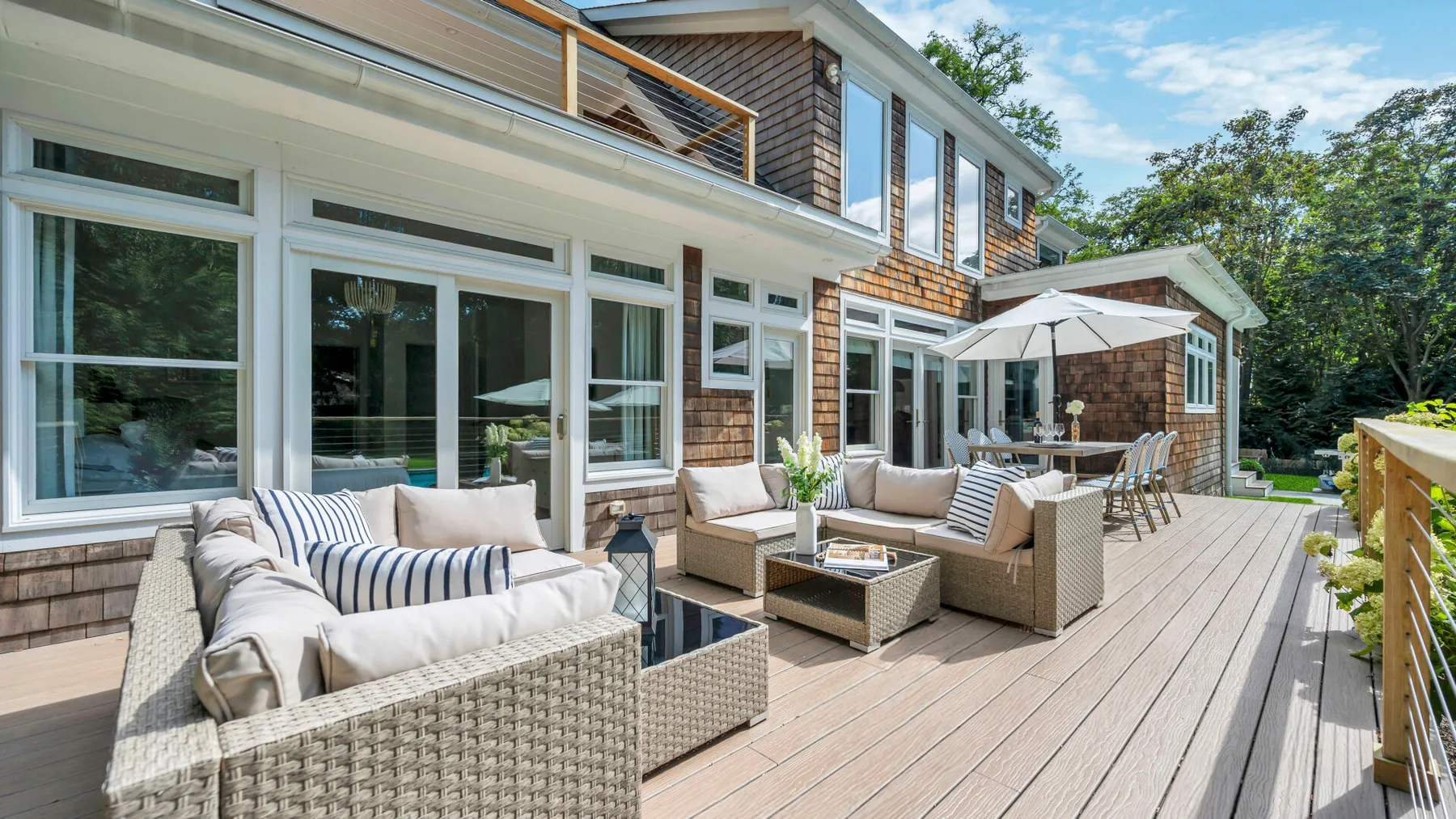 Una amplia terraza exterior con asientos acolchados y una sombrilla blanca.