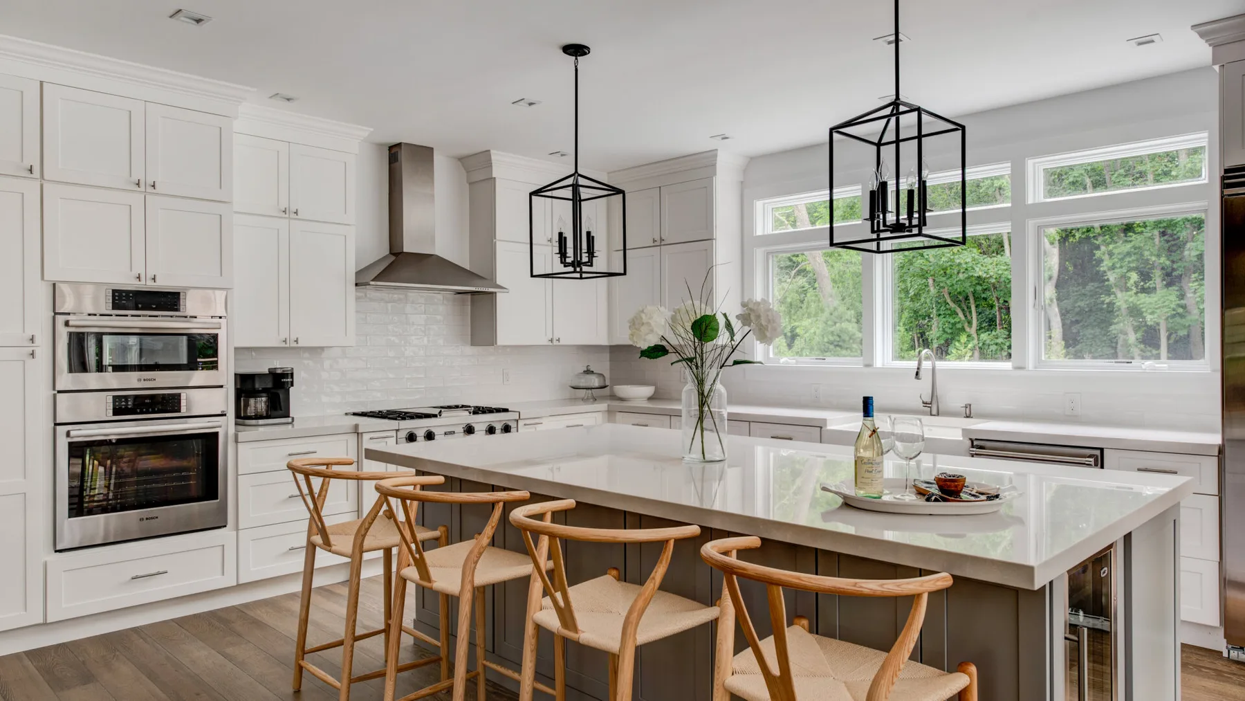 Una cocina luminosa con una isla grande, lámparas colgantes y ventanas amplias.