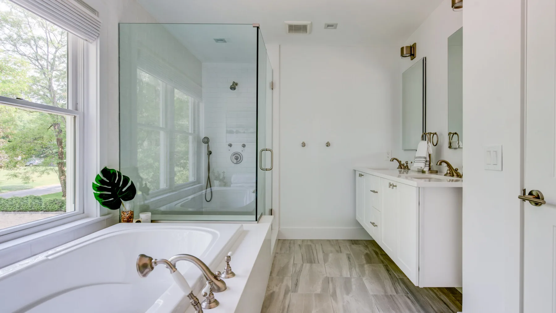 Un baño luminoso con bañera, ducha de vidrio y un largo tocador.