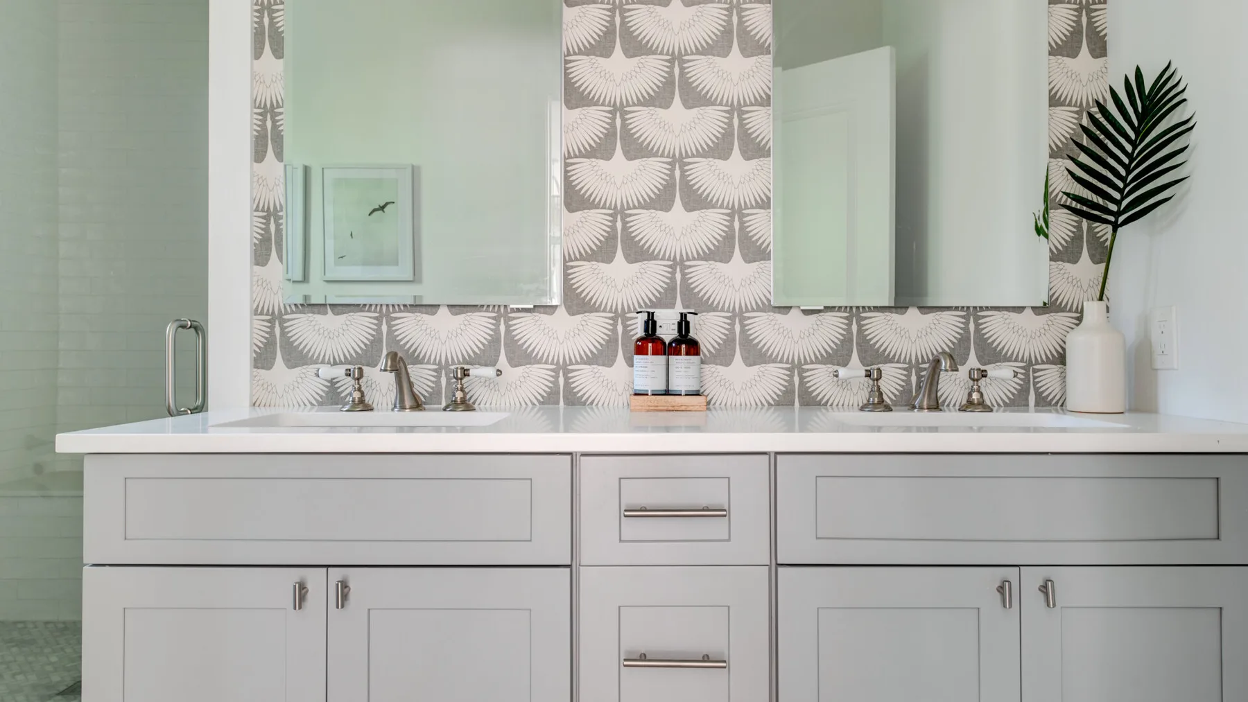 Un tocador de baño con una amplia encimera, espejos y azulejos estampados.