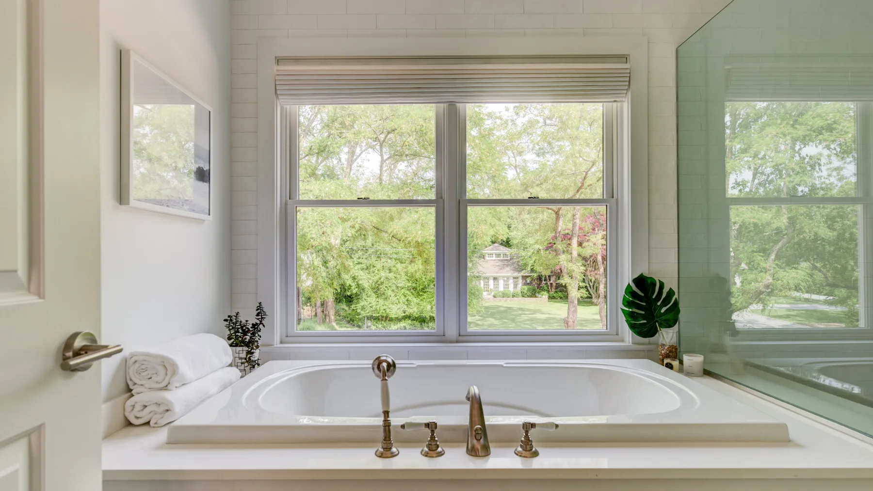 Un baño con una bañera amplia y ventanas que dan a la vegetación.