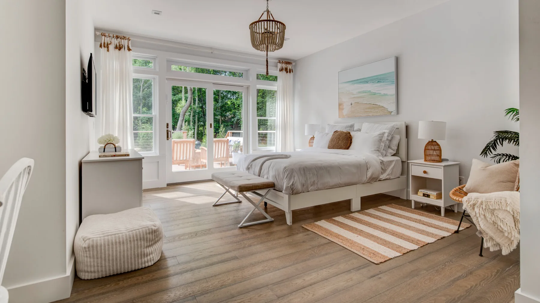 Un dormitorio luminoso con una cama junto a grandes ventanas y puertas de vidrio.