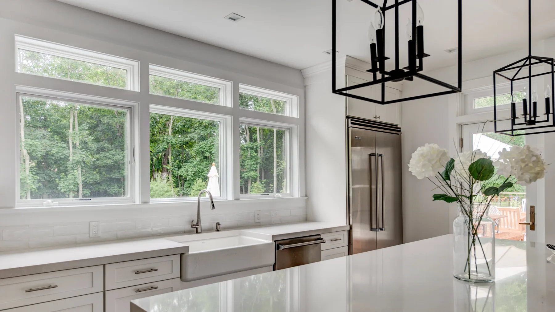 Una cocina luminosa con una encimera larga y grandes ventanas con vistas a la vegetación.