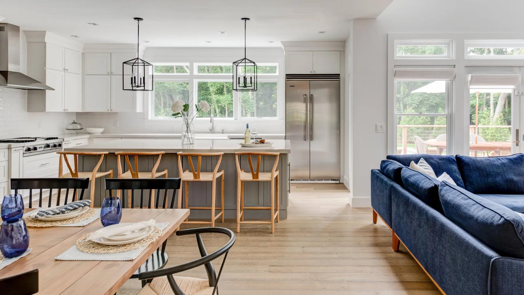 Cocina y sala de estar diáfanas y luminosas, con una isla y asientos azules.