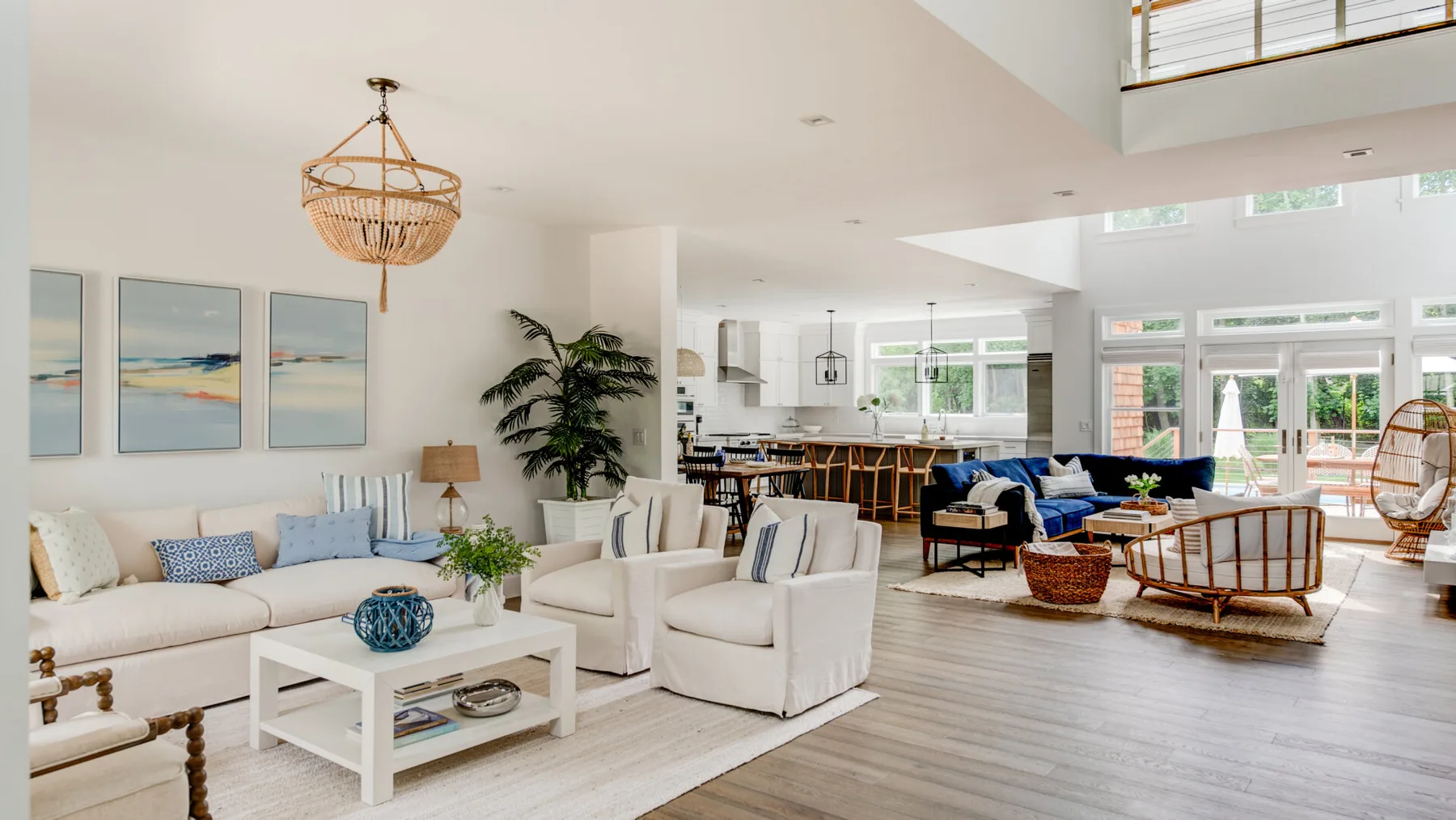 A bright open-plan living room with seating and a dining area beyond.