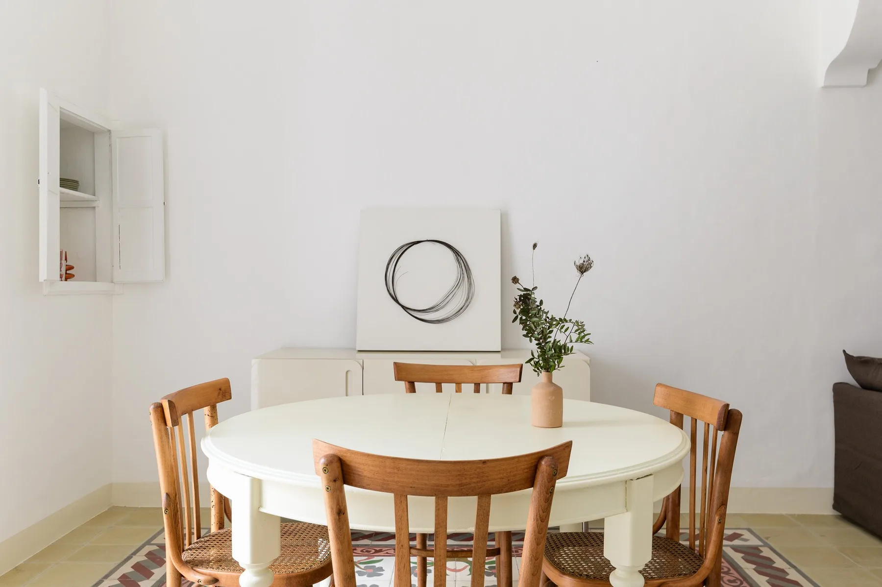 A bright dining area with a round table and wooden seating.