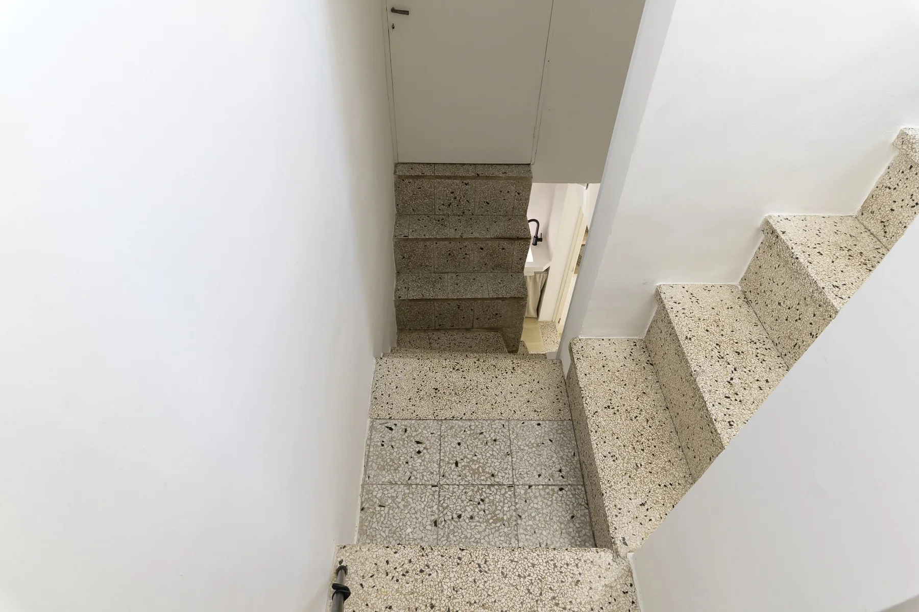 A narrow indoor stairway with speckled steps and a landing.