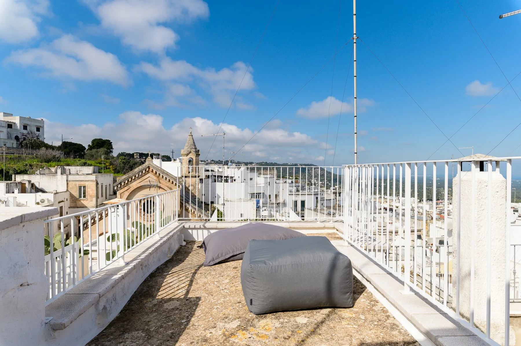 A rooftop terrace with cushioned seating and white railings overlooks the surrounding buildings.