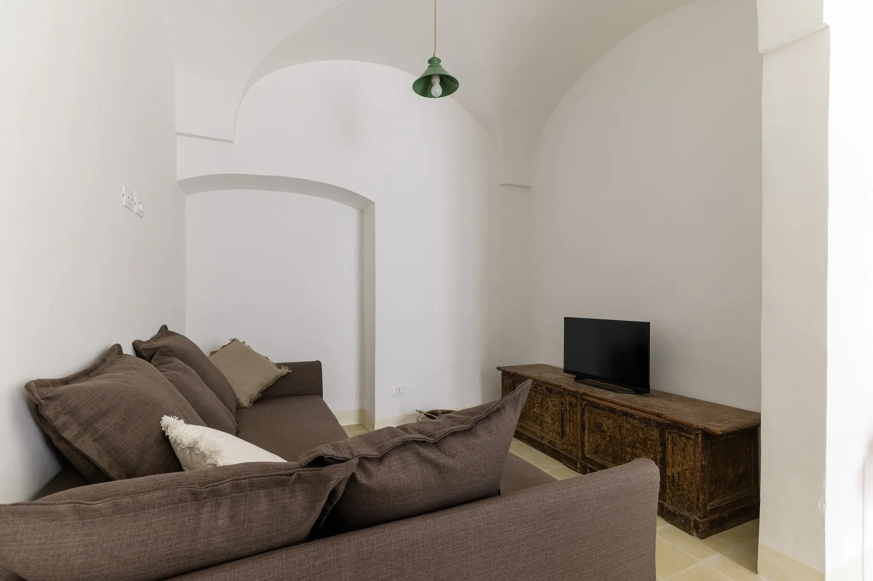 A living room with brown seating and a television on a wooden cabinet.