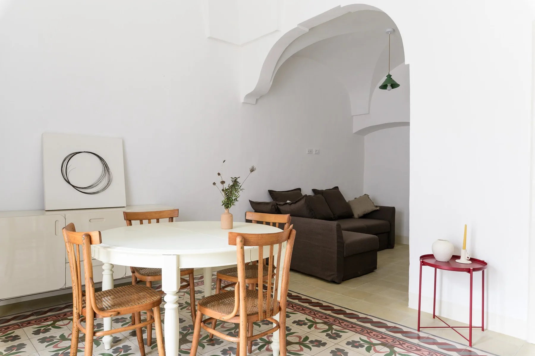 A dining area with a round table and chairs beside a dark sofa.