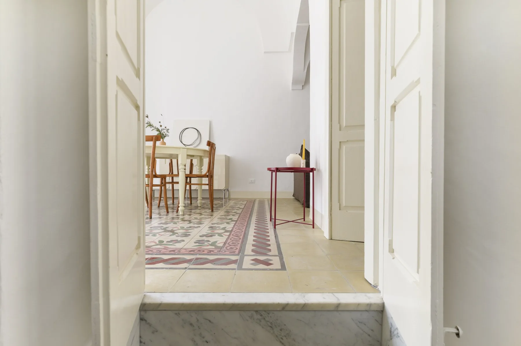 A bright dining area with a wooden table and patterned floor tiles.