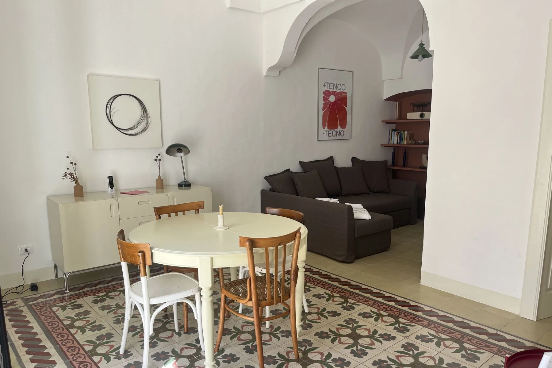 A dining area with a table and chairs opens onto a living area with seating.