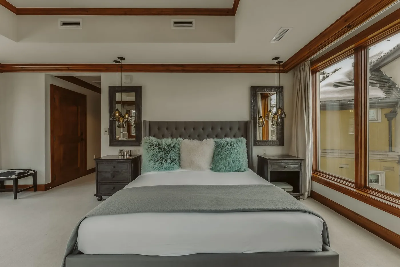 Un dormitorio con una cama bien tendida y grandes ventanas a un lado.