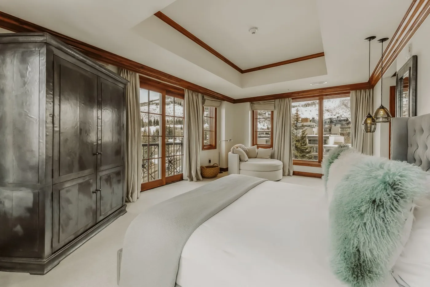 Un dormitorio luminoso con una cama grande y ventanas altas con vistas a la vegetación.
