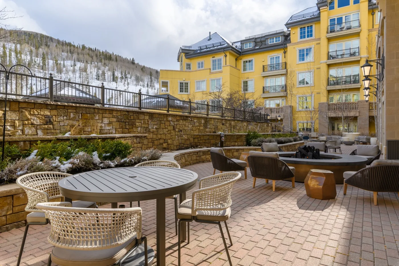 Un patio al aire libre con mesas y asientos junto a un edificio amarillo.