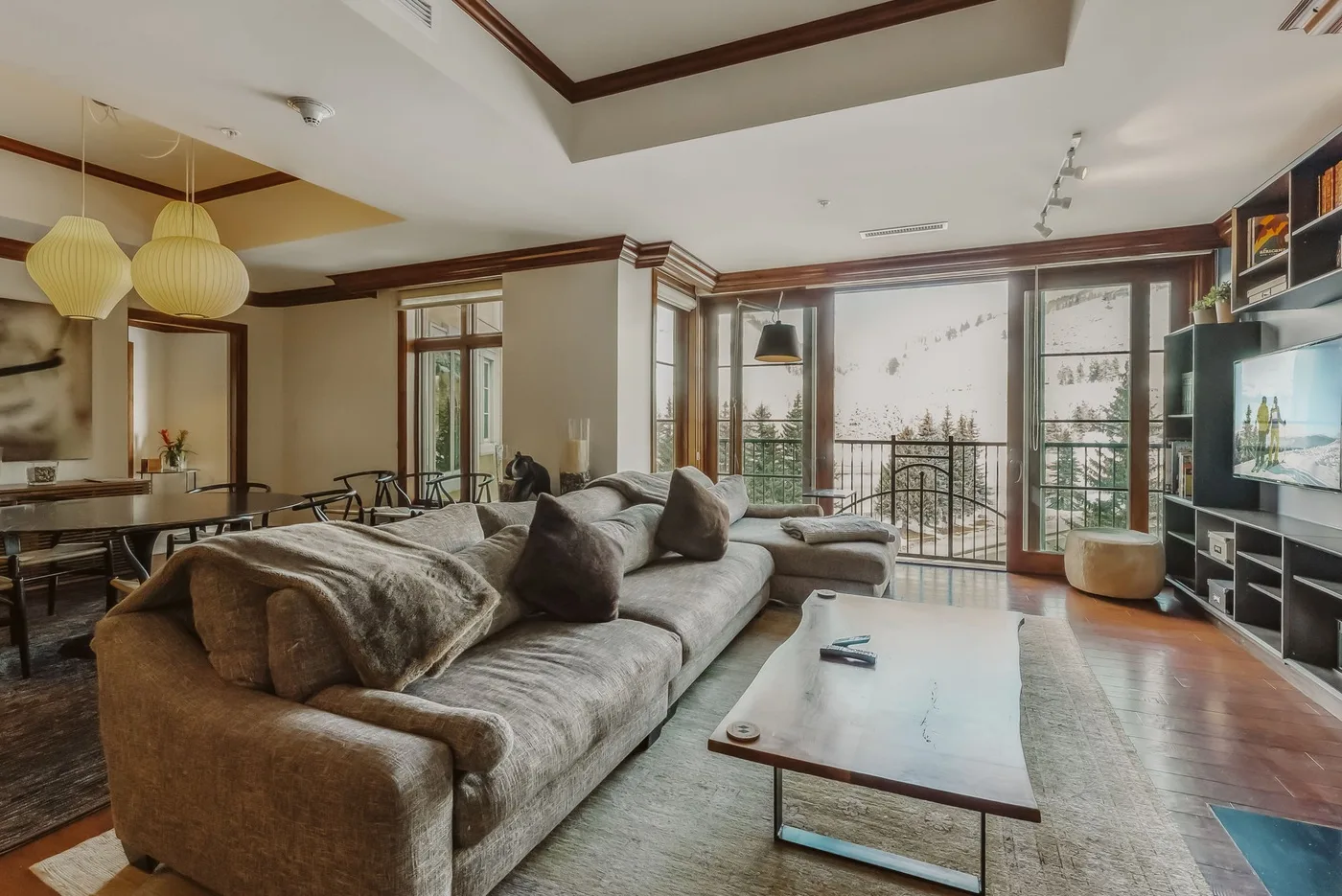 Una sala de estar con un sofá seccional grande y ventanas que dan a un balcón.