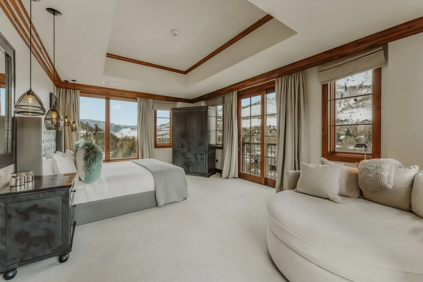 Un dormitorio con una cama y una zona de estar junto a grandes ventanas.