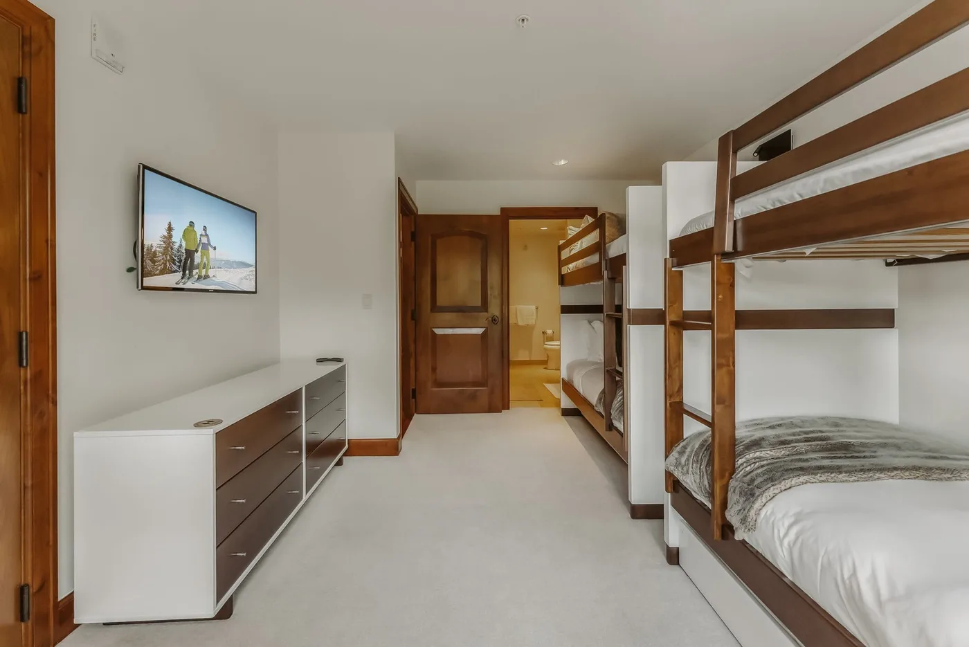 Un dormitorio con literas de madera y una cómoda baja junto a la pared.