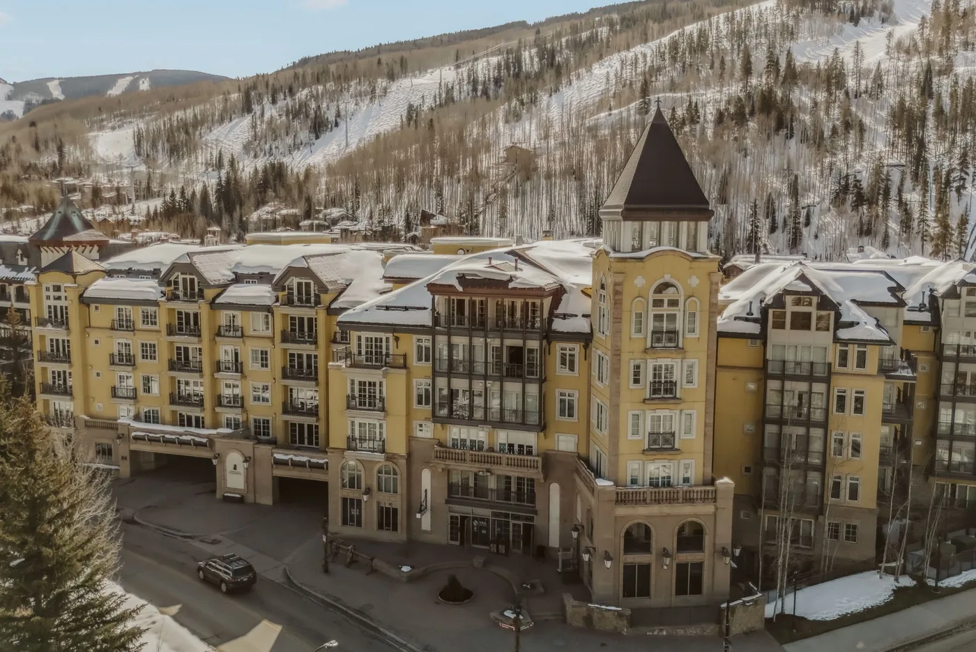 Un gran edificio hotelero se encuentra bajo una ladera montañosa cubierta de nieve.