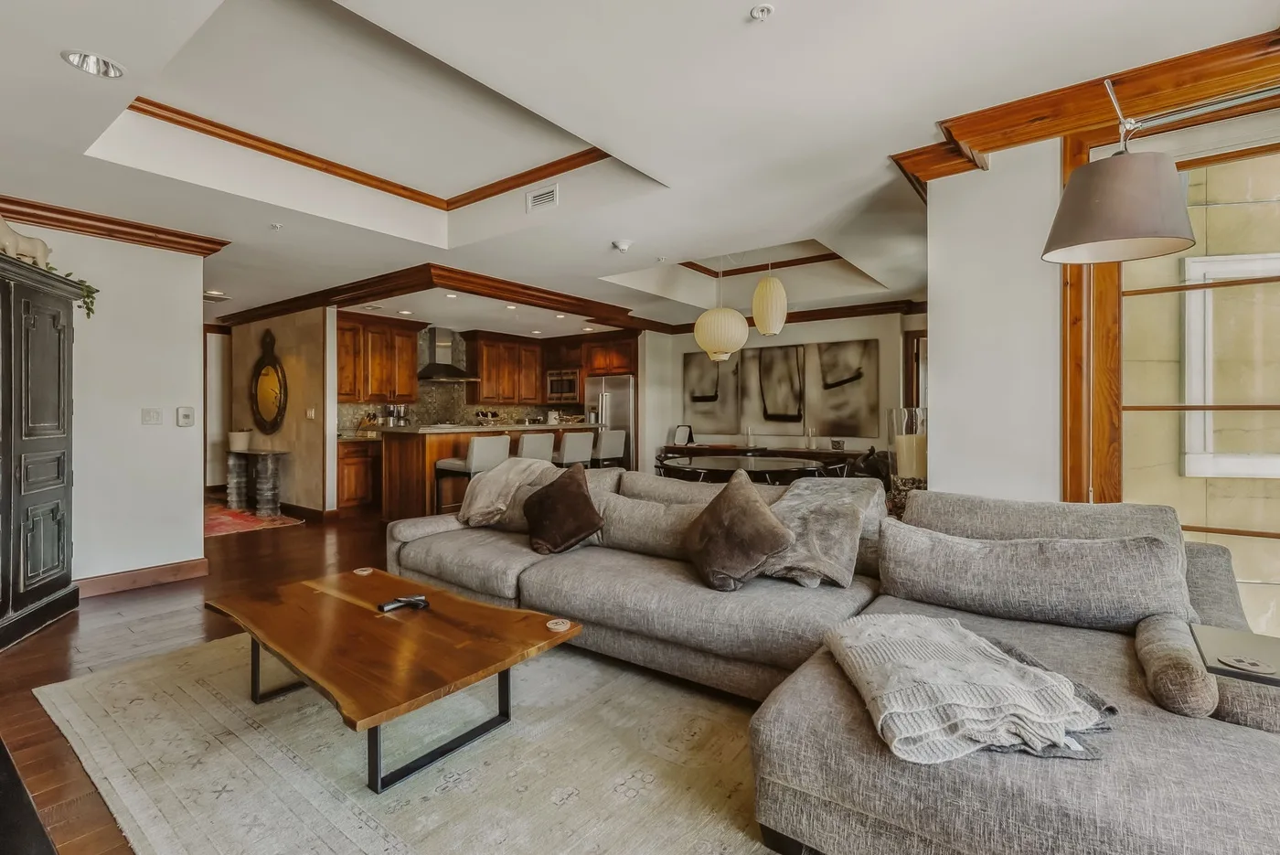 Sala de estar y cocina de planta abierta con asientos seccionales y una mesa de centro de madera.