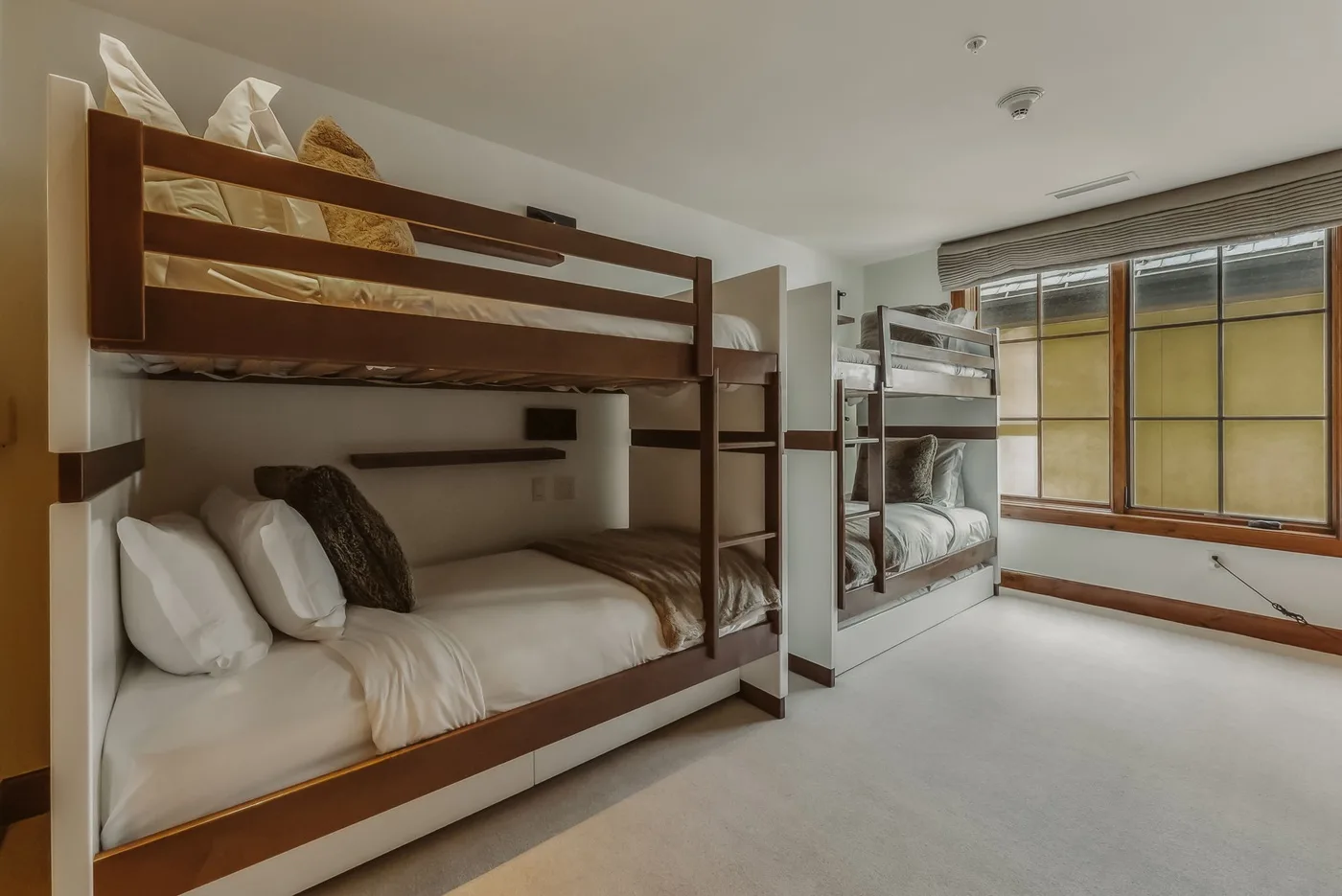 Un dormitorio con literas y grandes ventanas a lo largo de una pared.