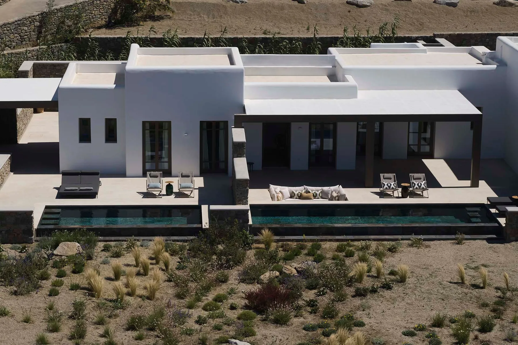 Una villa blanca moderna con una piscina larga y asientos al aire libre.