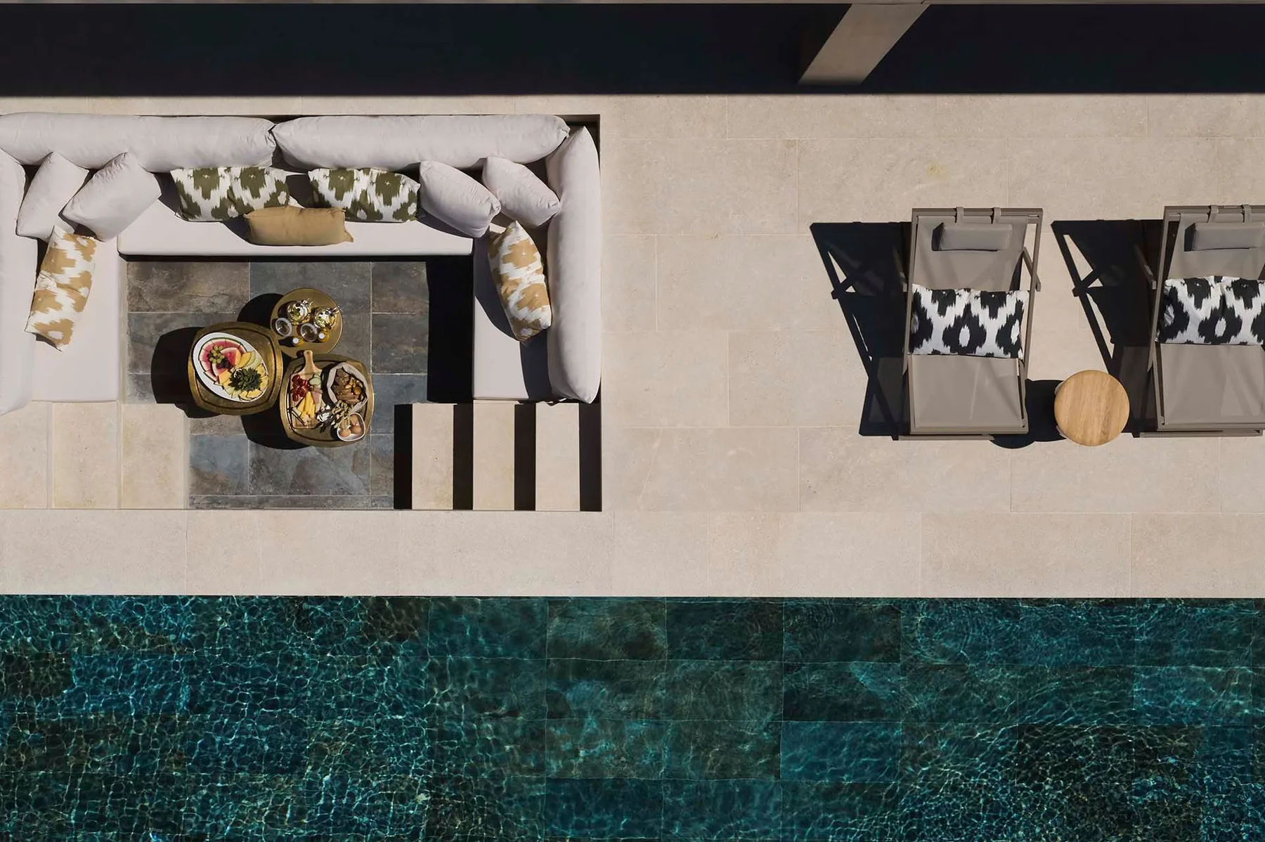 Zona de estar junto a una piscina exterior, con dos tumbonas al lado del agua.
