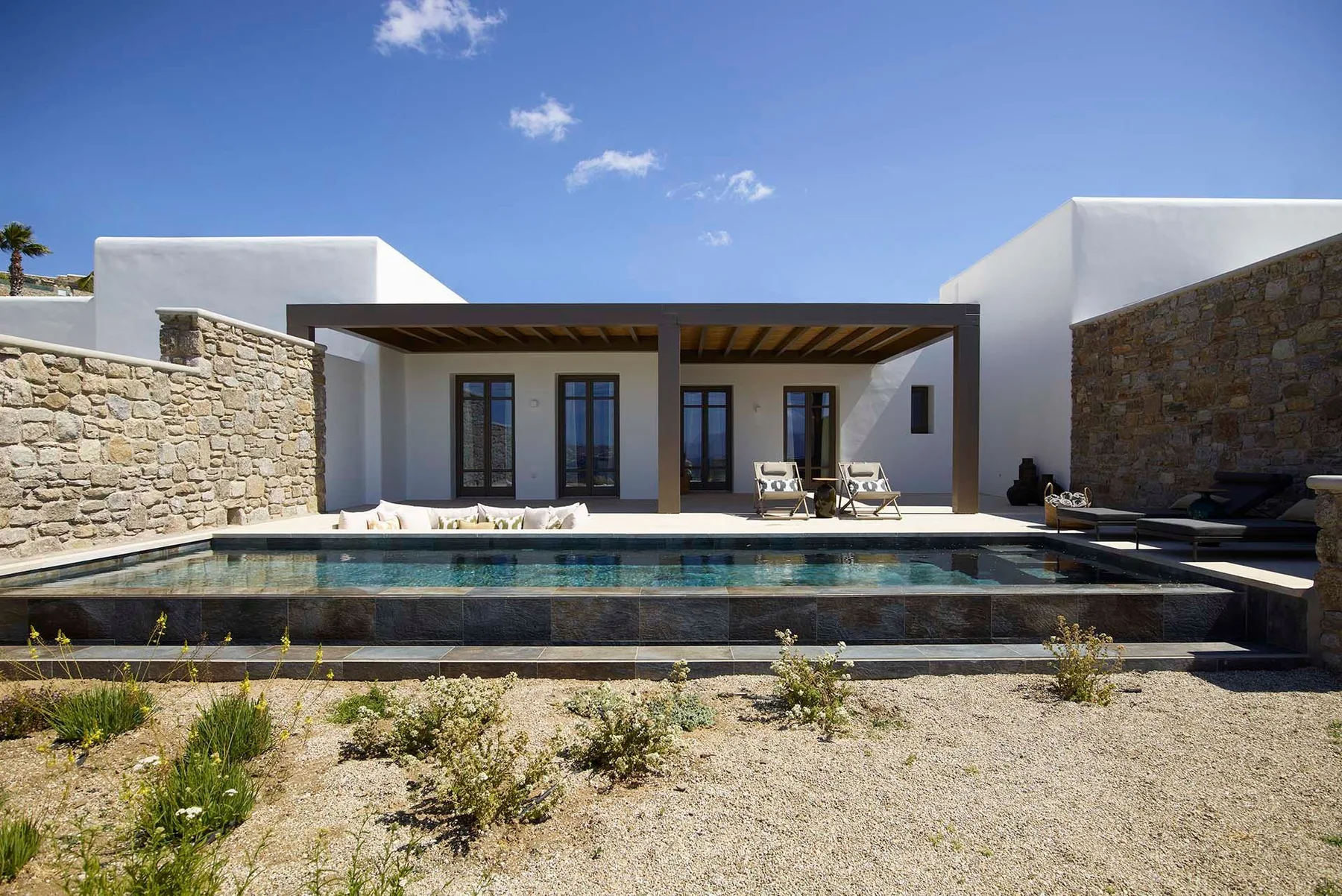 Una casa blanca moderna da a una piscina y un patio de piedra.