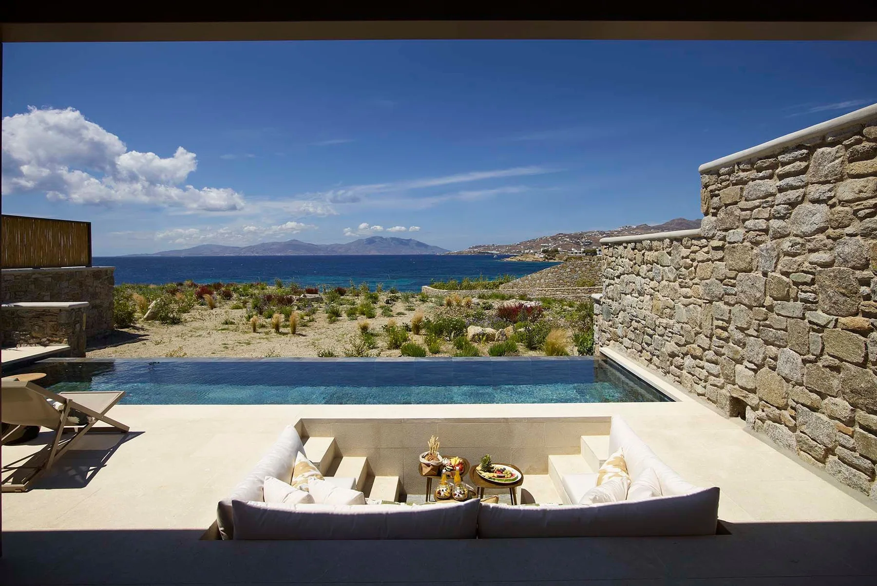 Una terraza junto al mar con piscina y asientos integrados, con vistas al agua.