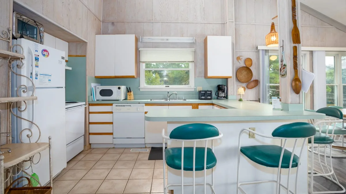 Una cocina luminosa con una isla central y gabinetes blancos.