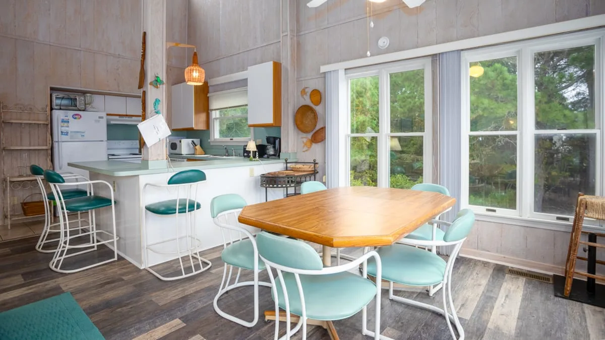 A bright kitchen and dining area with a wooden table and large windows.