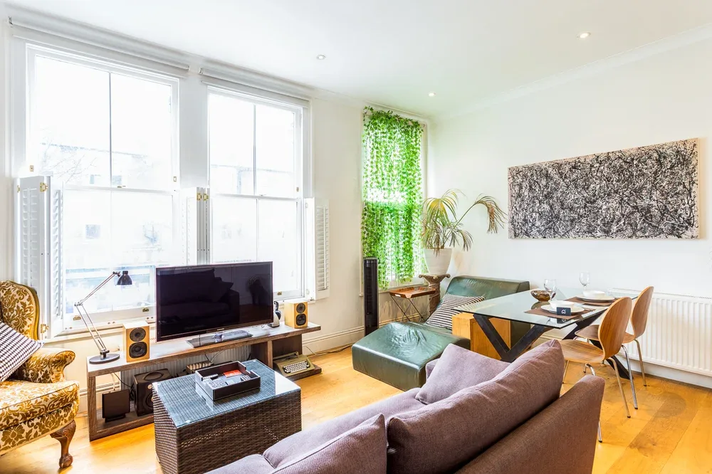 A bright living room with seating, a television, and large windows.