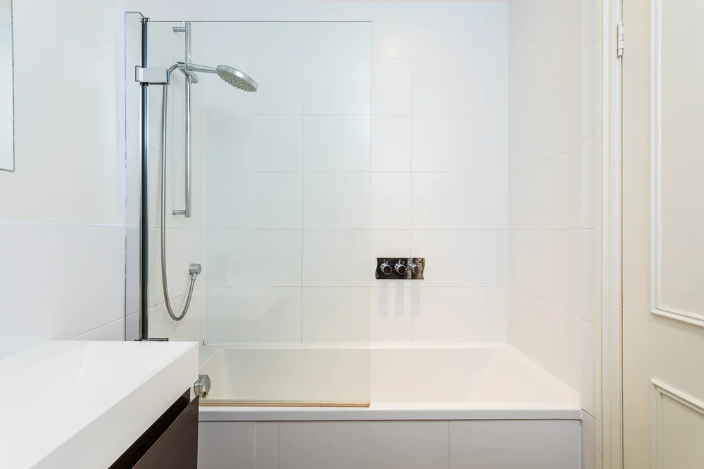 A bright bathroom with a bathtub and wall-mounted shower.