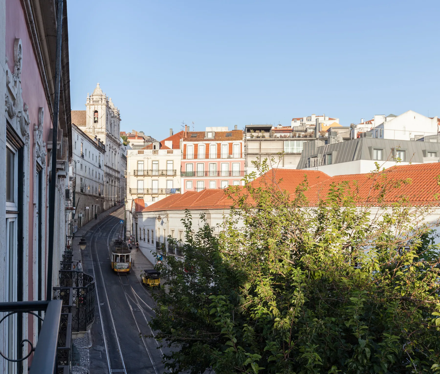 Una calle urbana discurre entre edificios históricos bajo un cielo azul despejado.