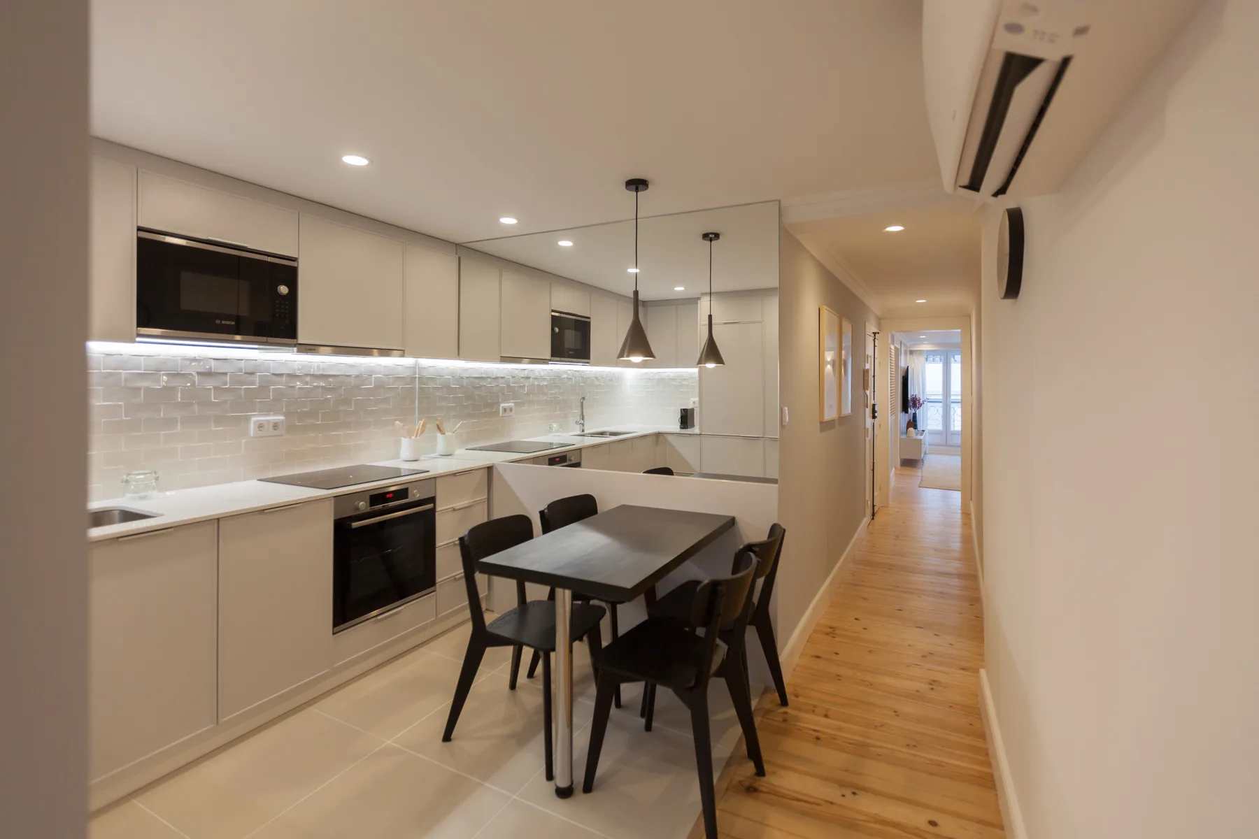 Cocina y comedor modernos con una mesa junto a un pasillo.