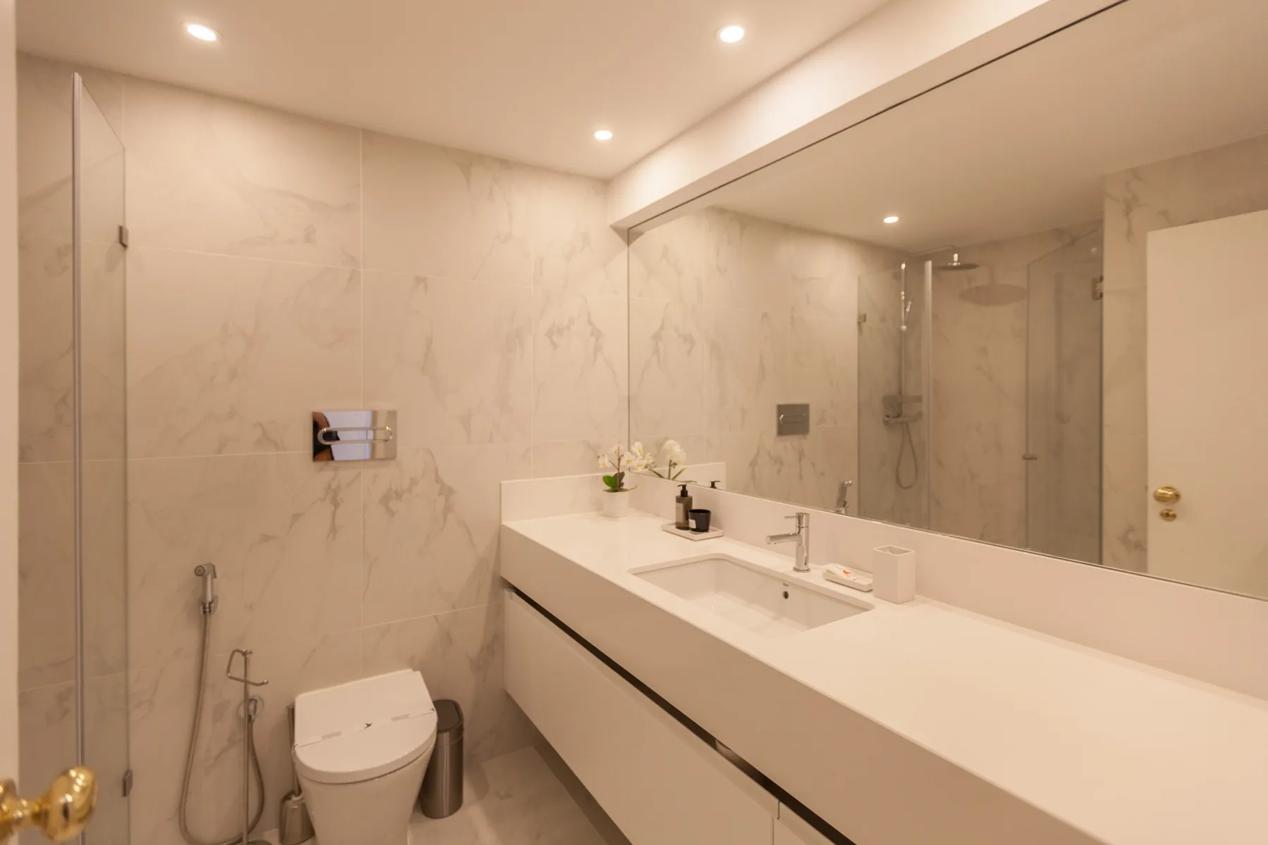 Un baño luminoso con un lavabo alargado y un espejo grande.
