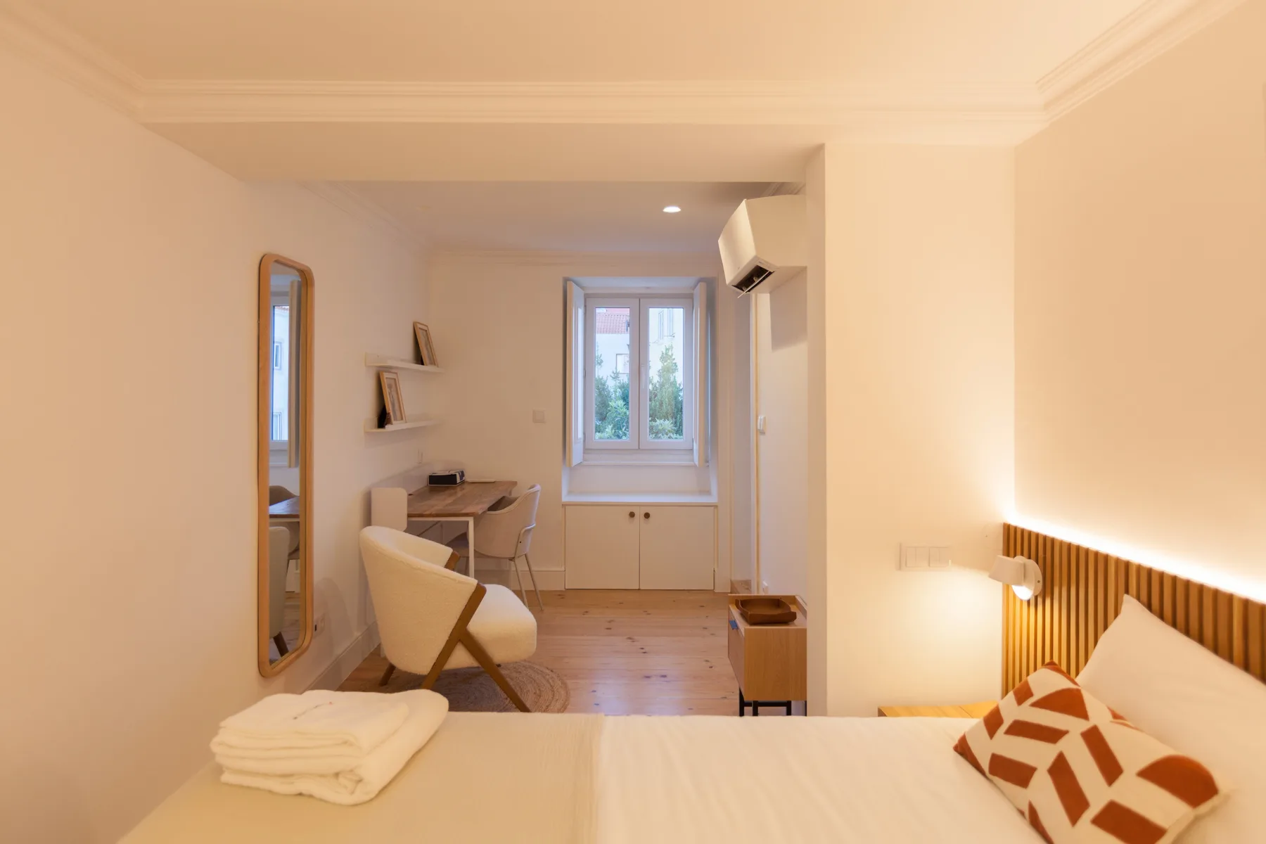 Un dormitorio con una cama, un escritorio y una ventana al fondo.