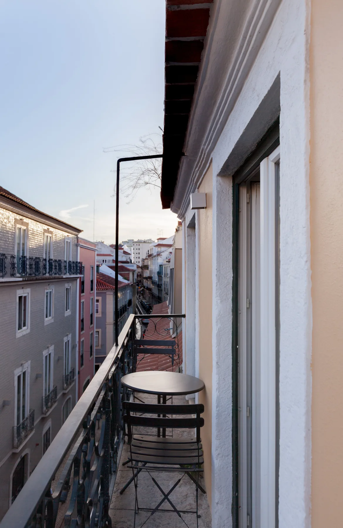 Un balcón estrecho da a una calle flanqueada por edificios muy juntos.