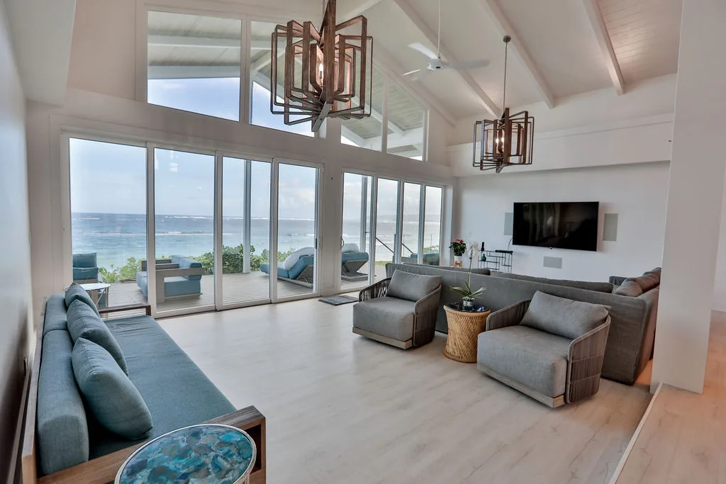 Una sala luminosa con asientos y grandes ventanales con vistas al mar.