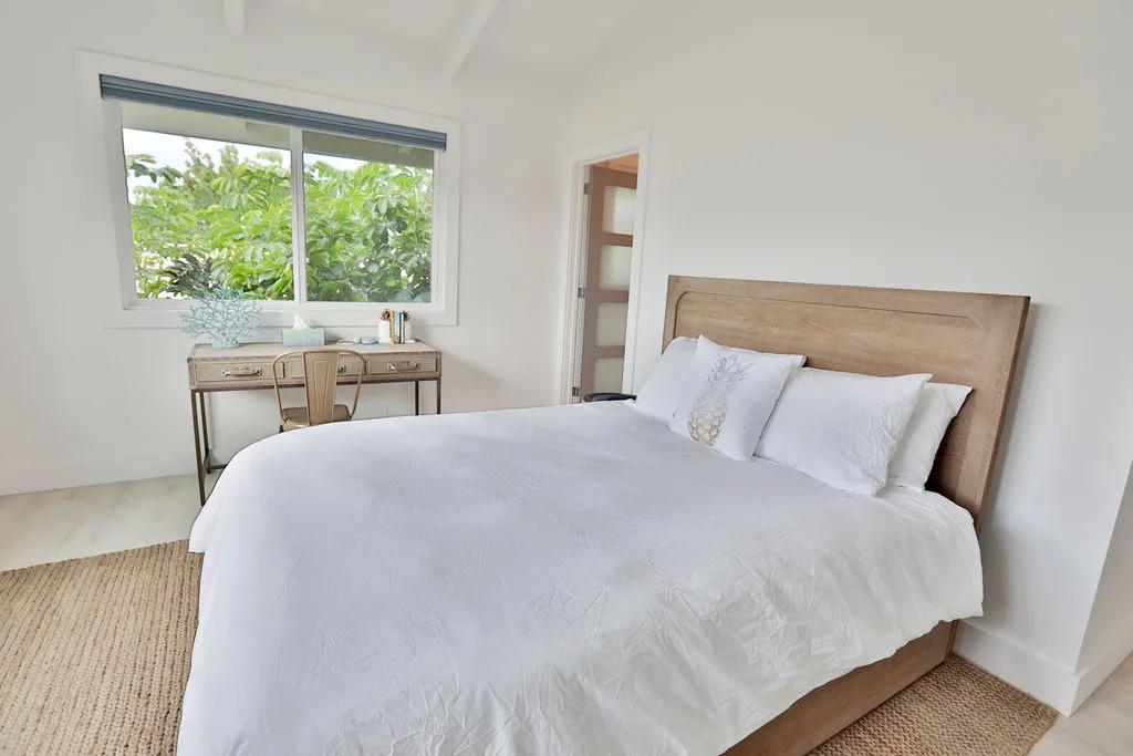 Un dormitorio luminoso con una cama y una ventana con vistas a la vegetación.