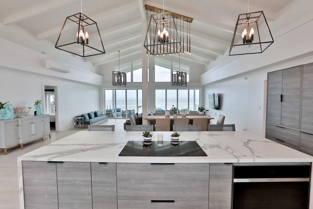 A bright open-plan kitchen and dining area with a large island and windows overlooking the water.
