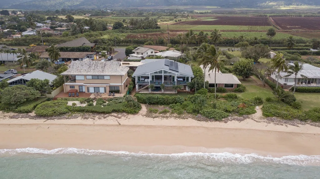 Vista aérea de casas frente a la playa junto a una orilla arenosa.