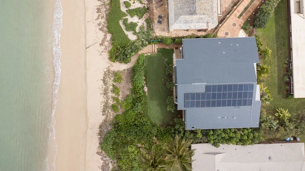 Una vista aérea muestra una casa junto a la playa con paneles solares.